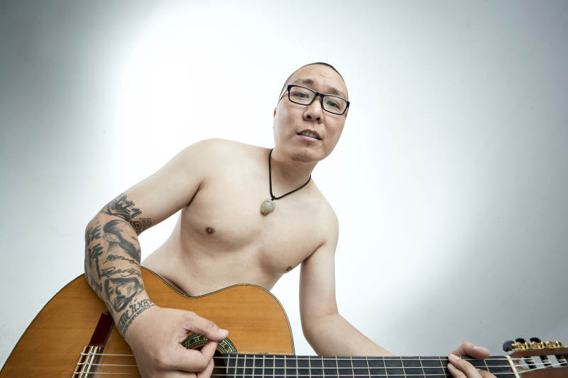 示范演奏古典吉他的亚洲男性乐手人像图片