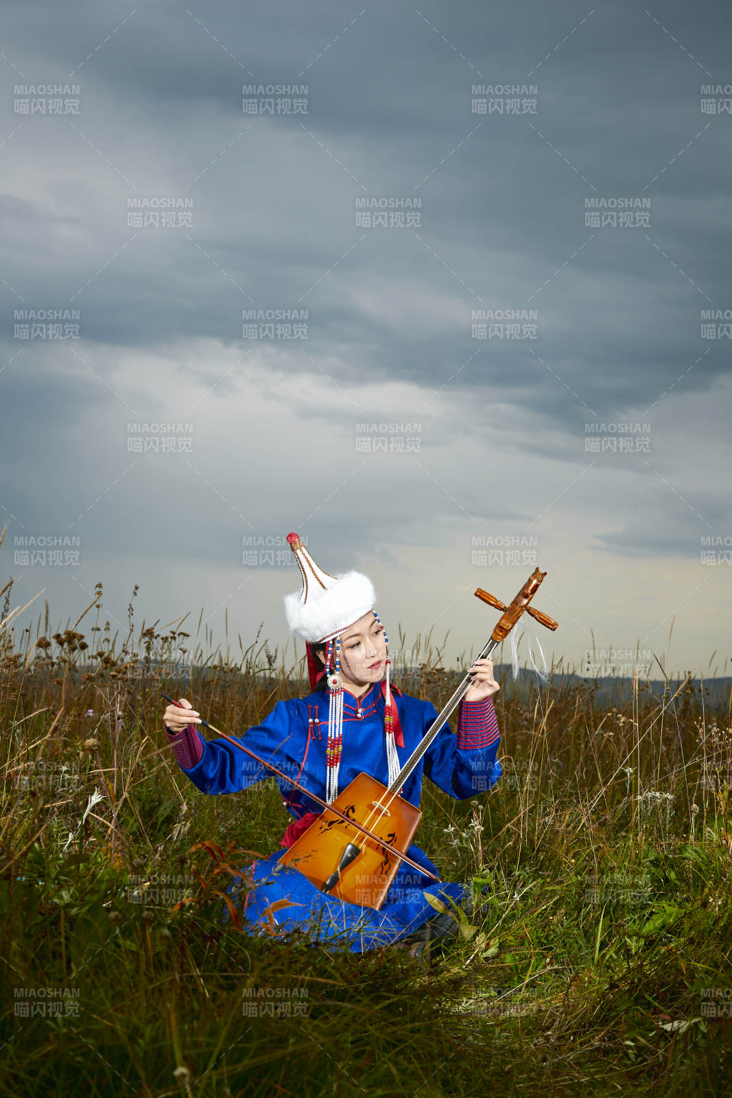 草原上穿蒙古族服饰拉马头琴的蒙族女乐手图片