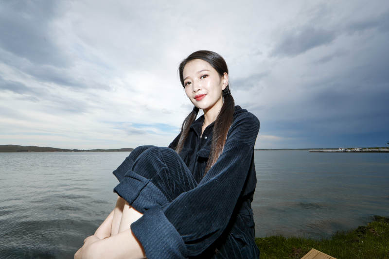 悠闲的坐在美丽湖岸码头的长发少女图片