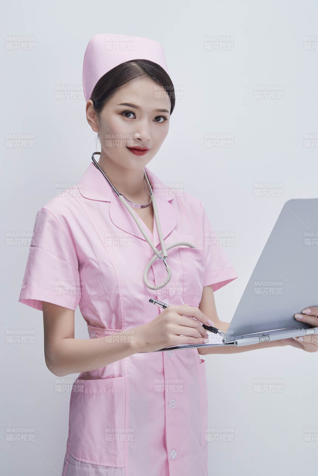 穿粉色护士服戴听诊器手持病历夹的医护人员图片