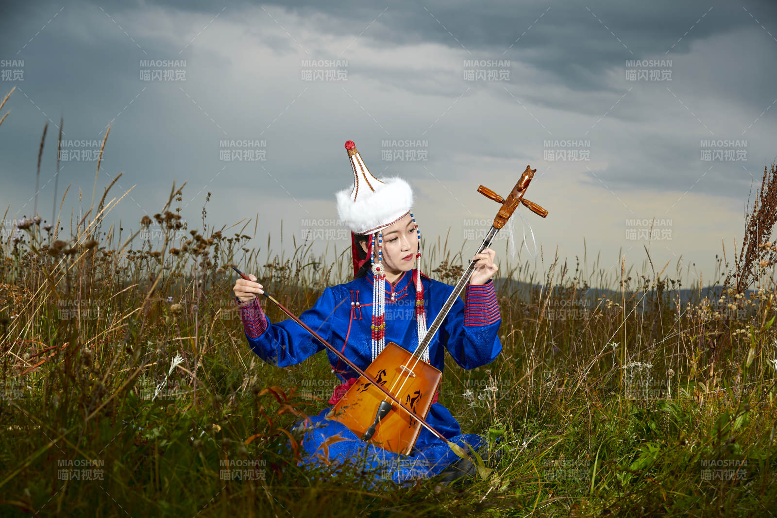 草原上穿蒙古族服饰拉马头琴的蒙族女乐手图片