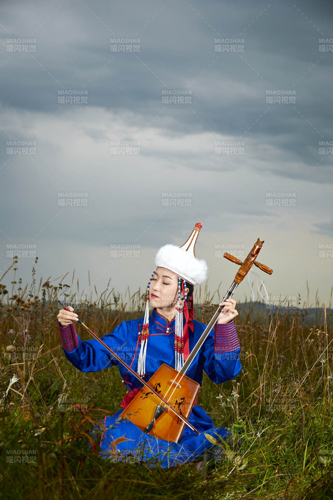 草原上穿蒙古族服饰拉马头琴的蒙族女乐手图片