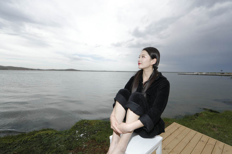 悠闲的坐在美丽湖岸码头的长发少女图片