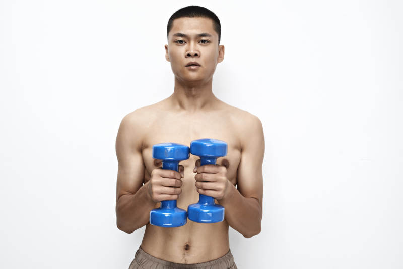 使用哑铃进行健身锻炼的亚洲男性图片