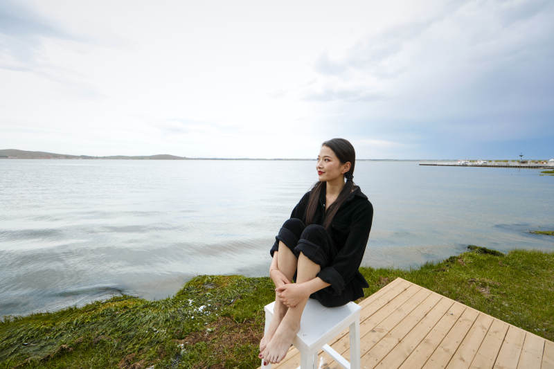 悠闲的坐在美丽湖岸码头的长发少女图片