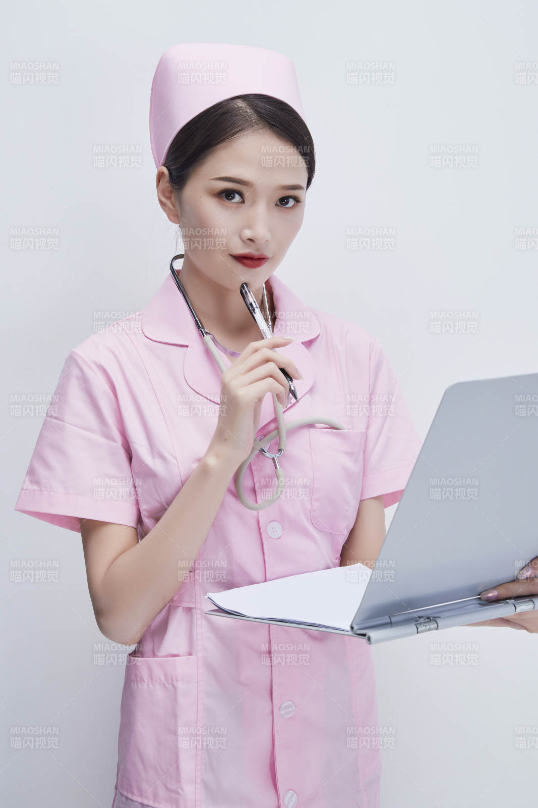 穿粉色护士服戴听诊器手持病历夹的医护人员图片