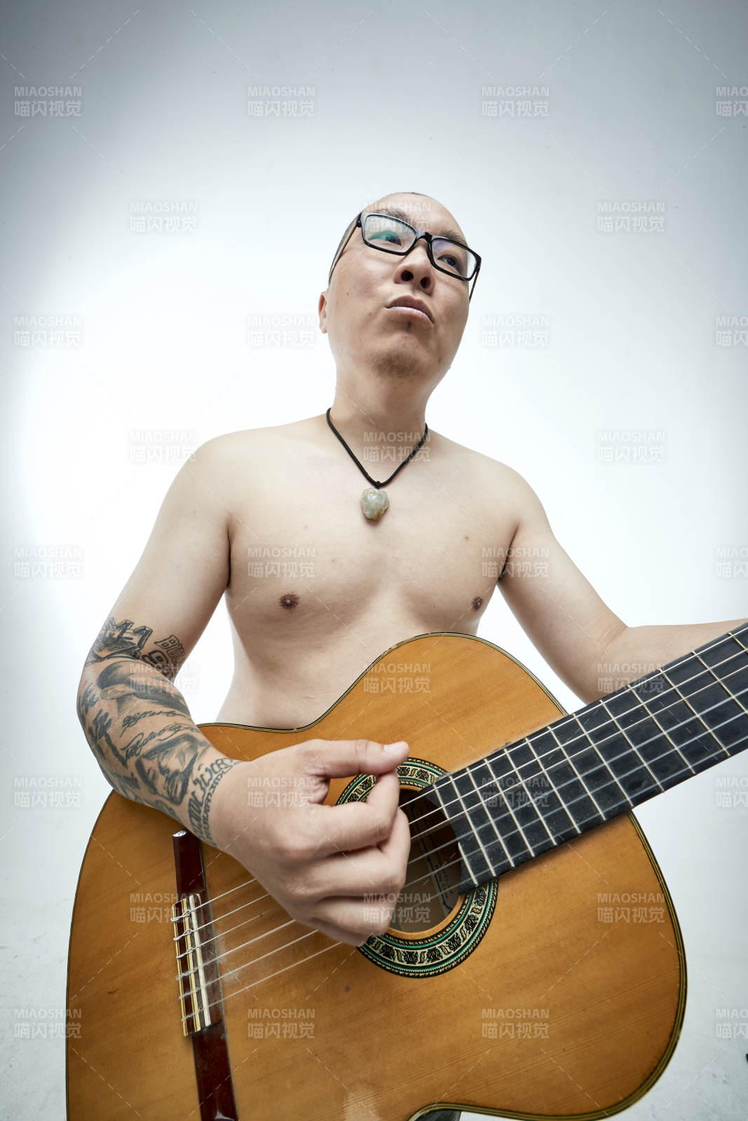 示范演奏古典吉他的亚洲男性乐手人像图片