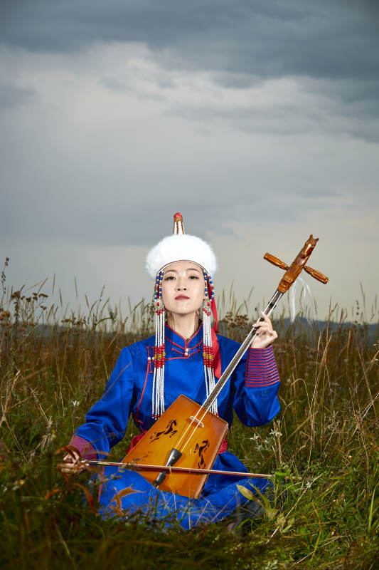 草原上穿蒙古族服饰拉马头琴的蒙族女乐手图片