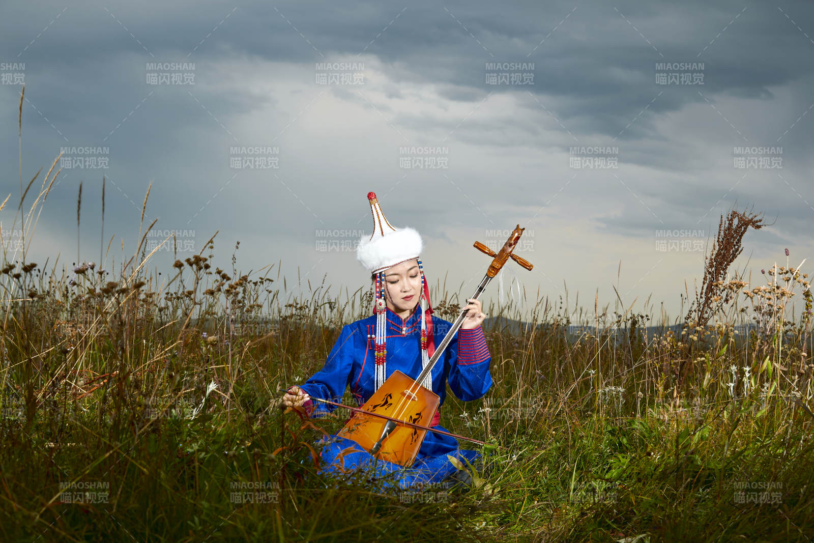 草原上穿蒙古族服饰拉马头琴的蒙族女乐手图片