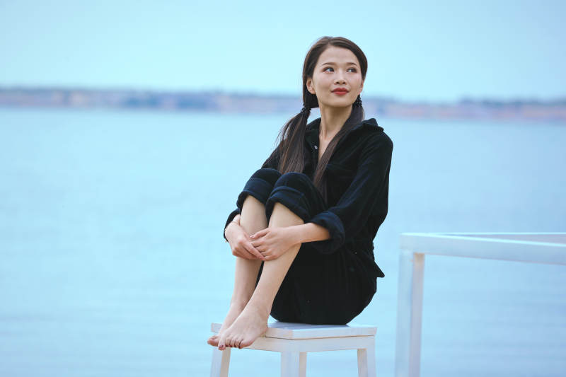 悠闲的坐在美丽湖岸码头的亚洲年轻女性人像图片