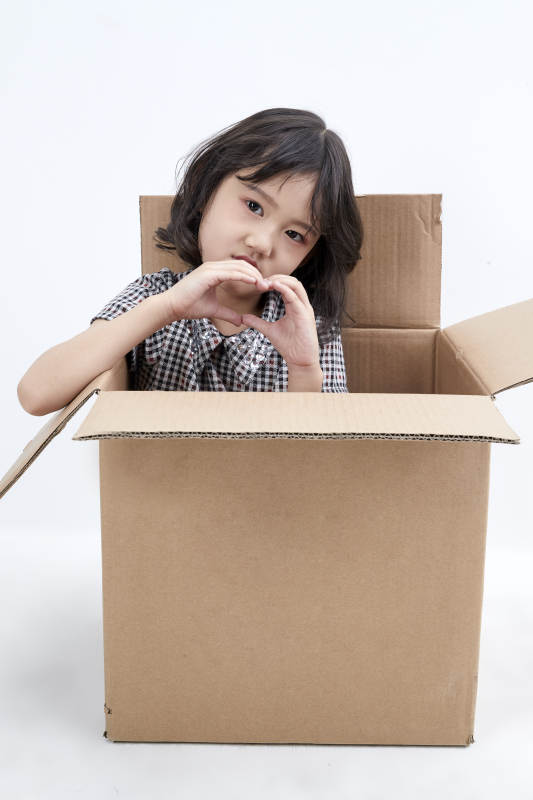 躲在纸箱中玩耍的调皮可爱亚洲小女孩儿童图片
