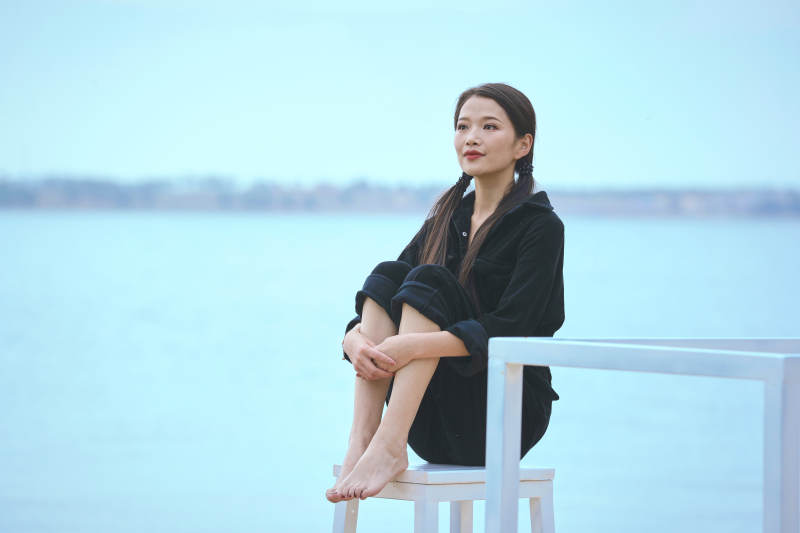 悠闲的坐在美丽湖岸码头的亚洲年轻女性人像图片