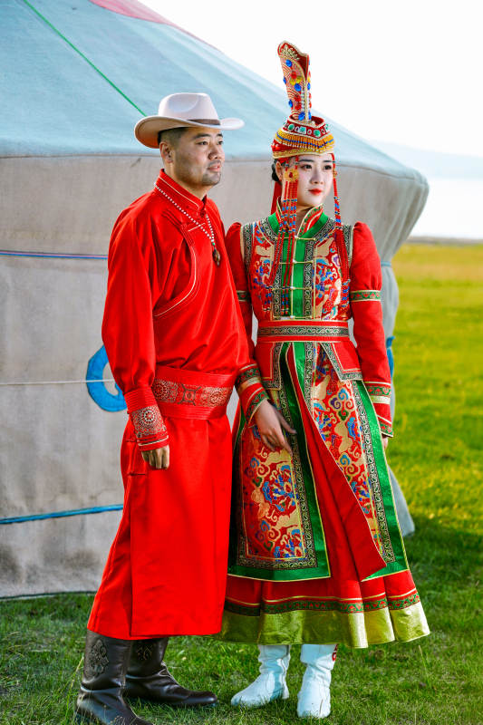 草原上蒙古包前穿蒙古族传统服饰的年轻夫妻图片