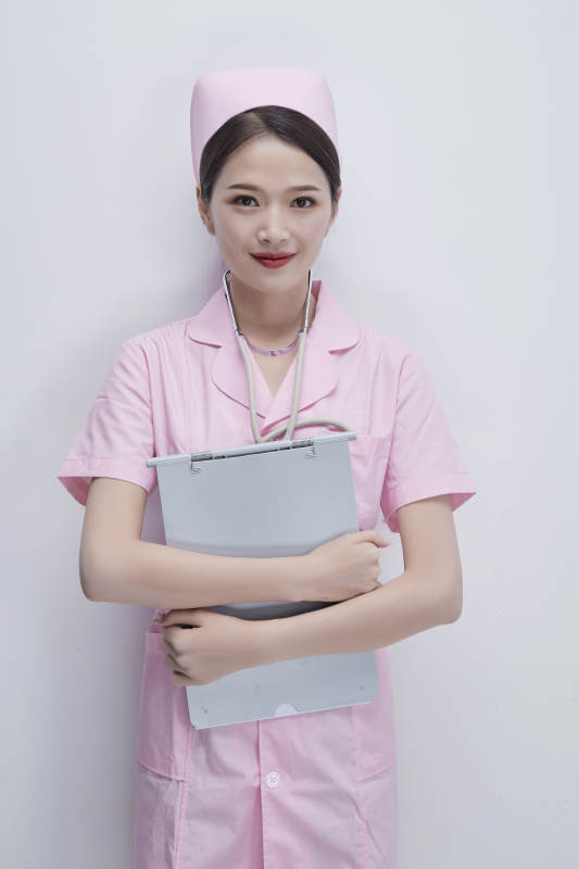 穿粉色护士服戴听诊器手持病历夹的医护人员图片