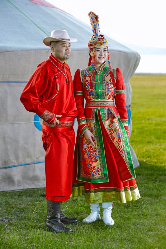 草原上蒙古包前穿蒙古族传统服饰的年轻夫妻图片