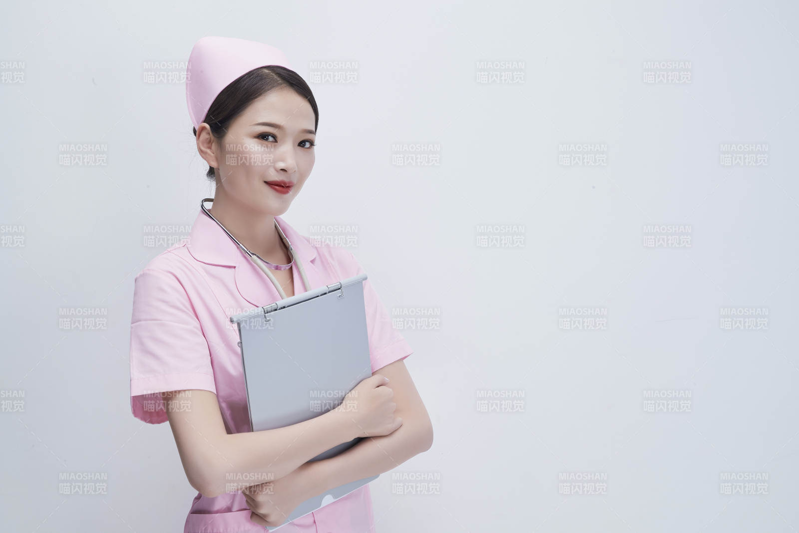 穿粉色护士服戴听诊器手持病历夹的医护人员图片