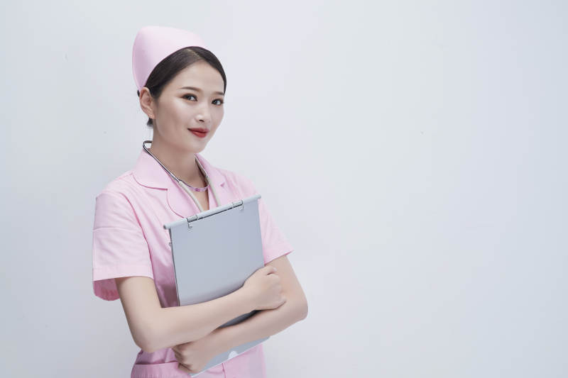 穿粉色护士服戴听诊器手持病历夹的医护人员图片