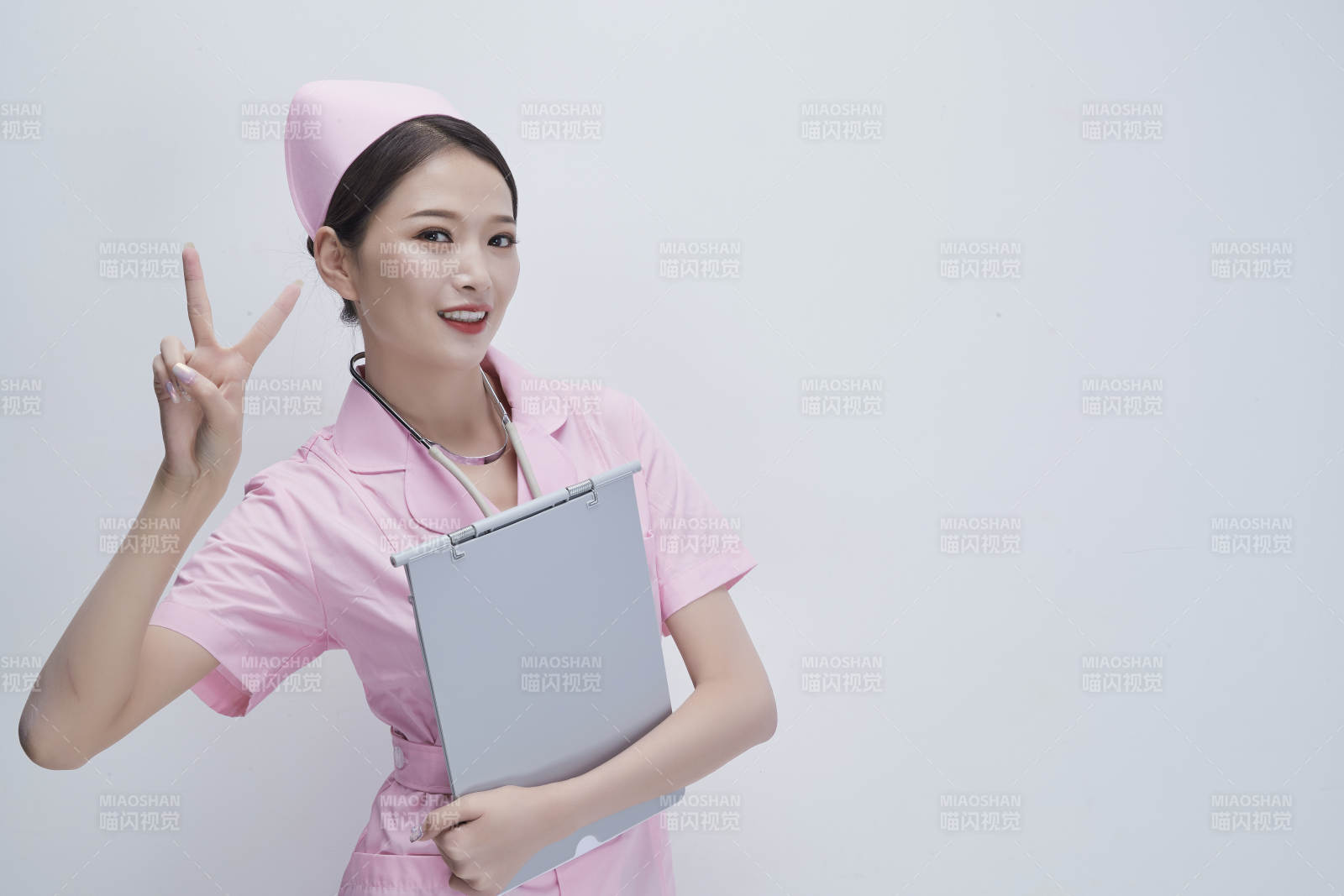 穿粉色护士服戴听诊器手持病历夹的医护人员图片