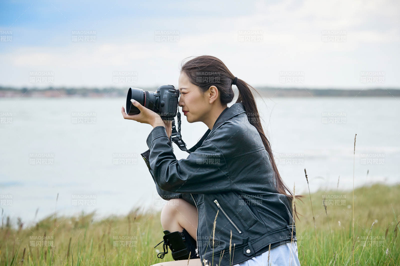 户外湖畔进行拍摄的亚洲青年女性摄影师图片
