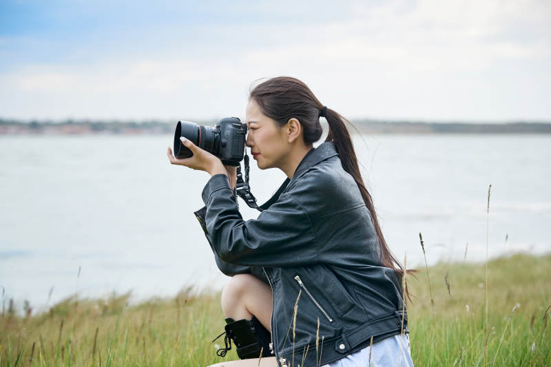 户外湖畔进行拍摄的亚洲青年女性摄影师图片