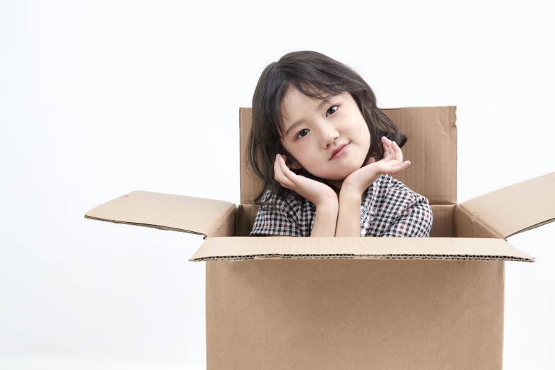 躲在纸箱中玩耍的调皮可爱亚洲小女孩儿童图片