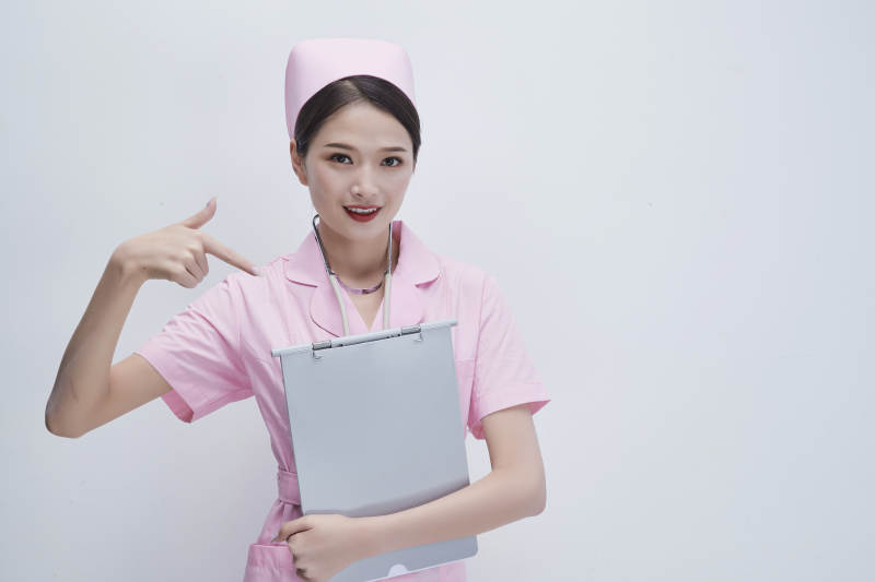 穿粉色护士服戴听诊器手持病历夹的医护人员图片