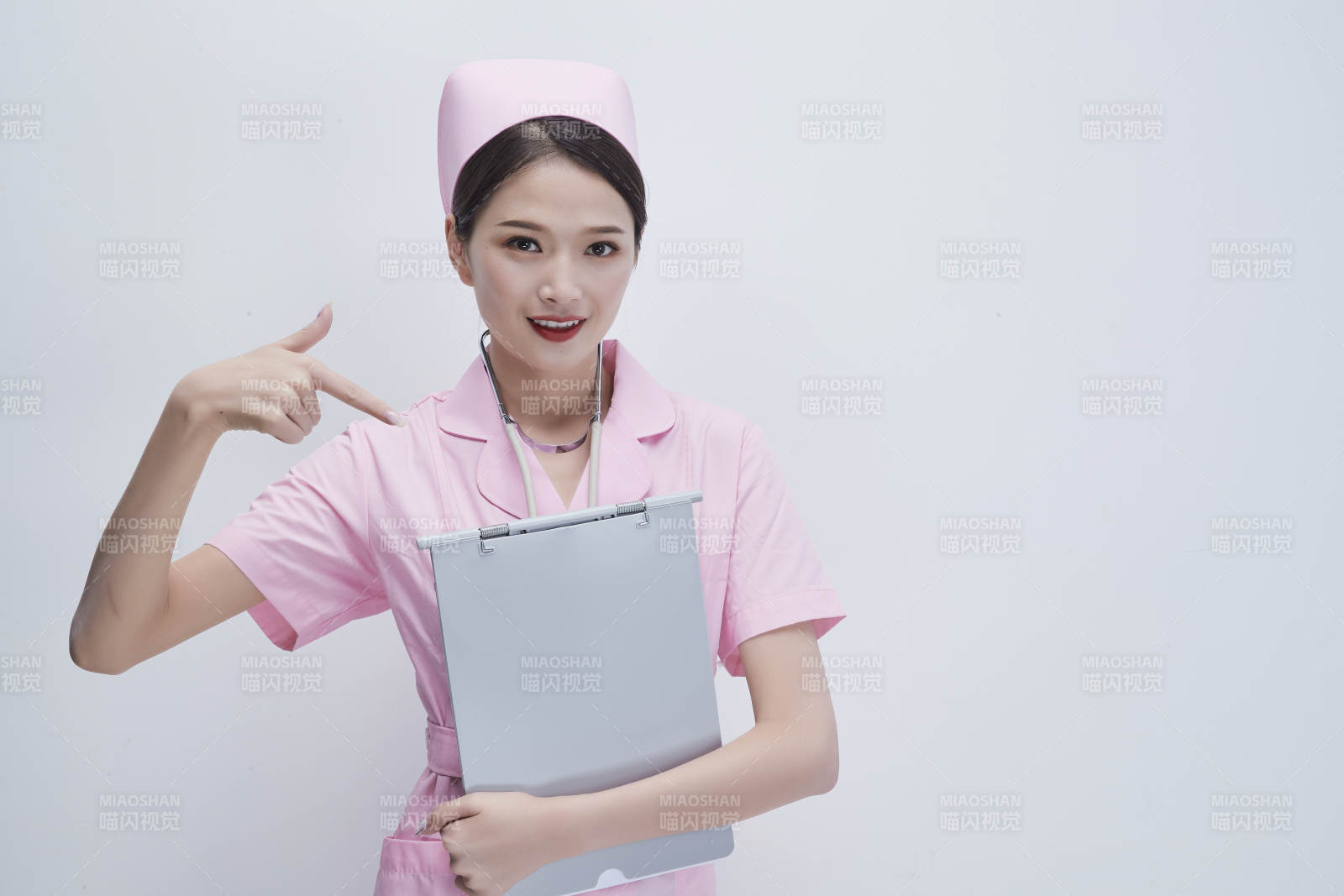 穿粉色护士服戴听诊器手持病历夹的医护人员图片