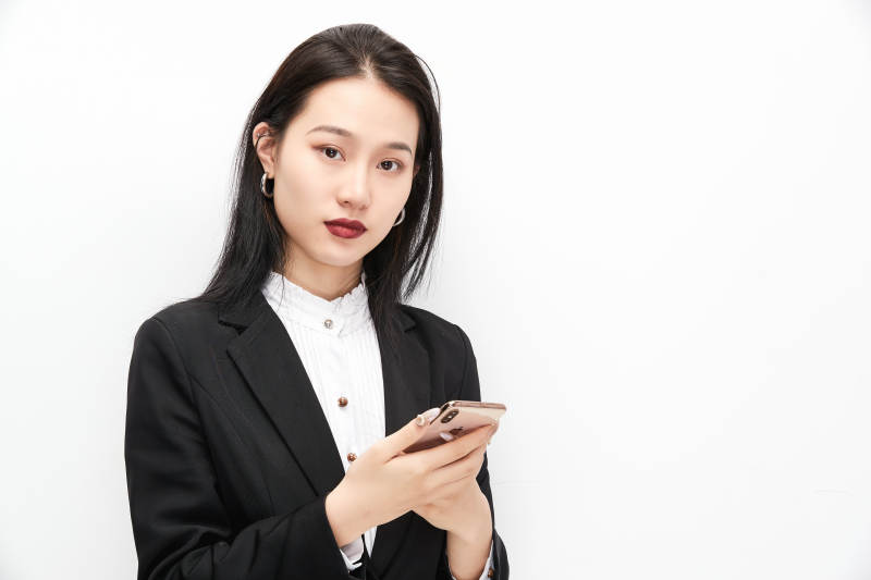 身穿西服拿着手机的美丽商务女士图片