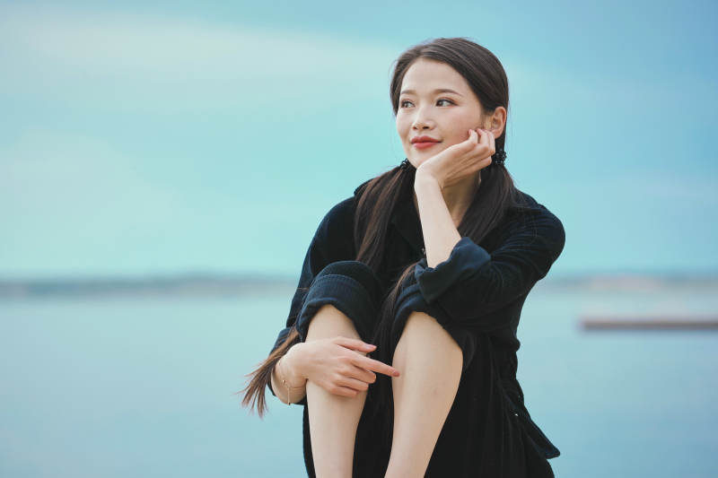 悠闲的坐在美丽湖岸码头的亚洲年轻女性人像图片