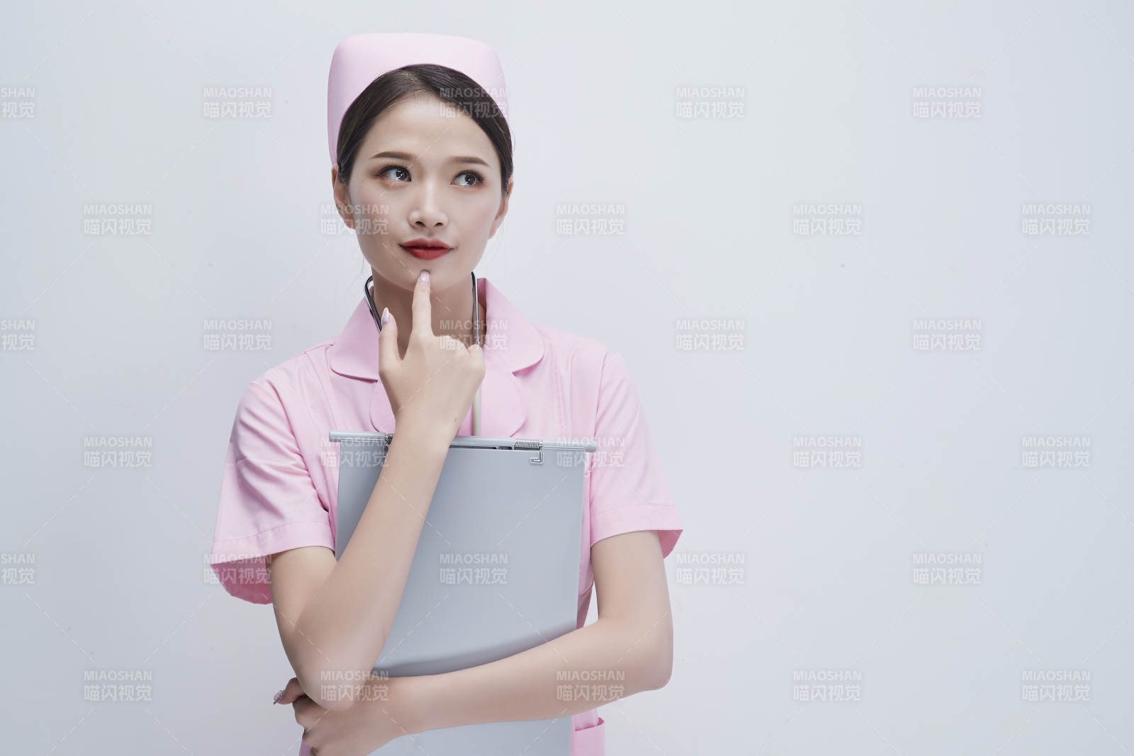 穿粉色护士服戴听诊器手持病历夹的医护人员图片