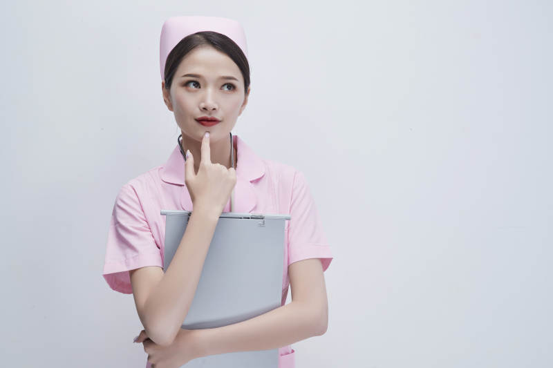 穿粉色护士服戴听诊器手持病历夹的医护人员图片