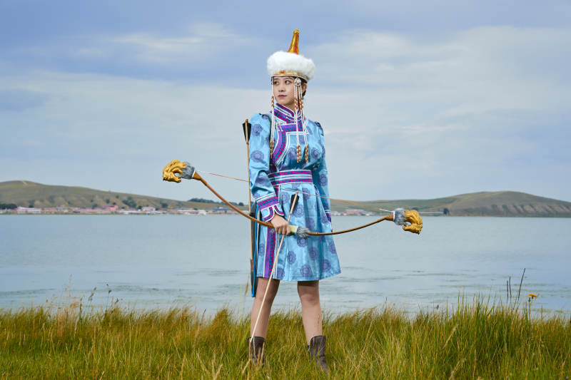 草原湖畔身穿蒙古族饰手持弓箭的蒙族少女图片