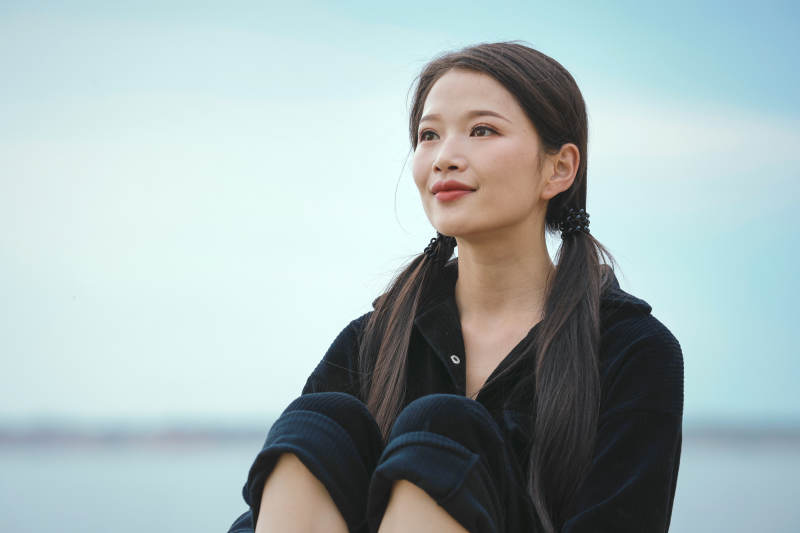 悠闲的坐在美丽湖岸码头的亚洲年轻女性人像图片