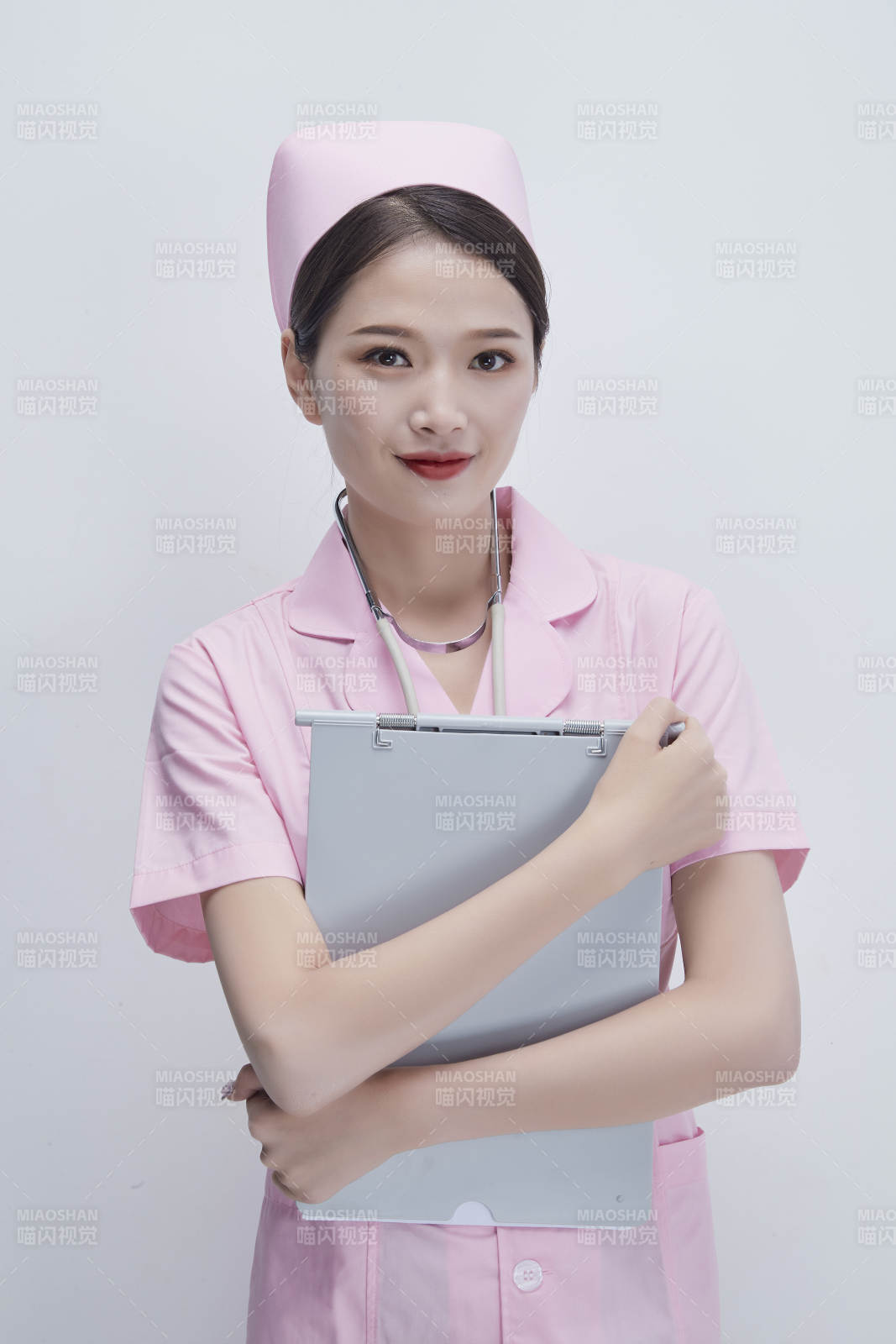穿粉色护士服戴听诊器手持病历夹的医护人员图片