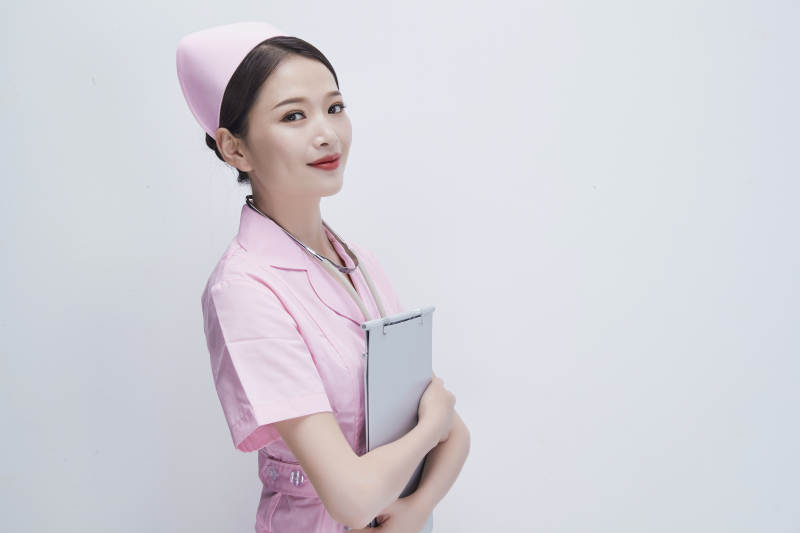 穿粉色护士服戴听诊器手持病历夹的医护人员图片