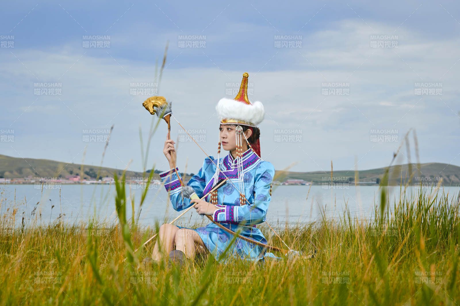 草原湖畔身穿蒙古族饰手持弓箭的蒙族少女图片