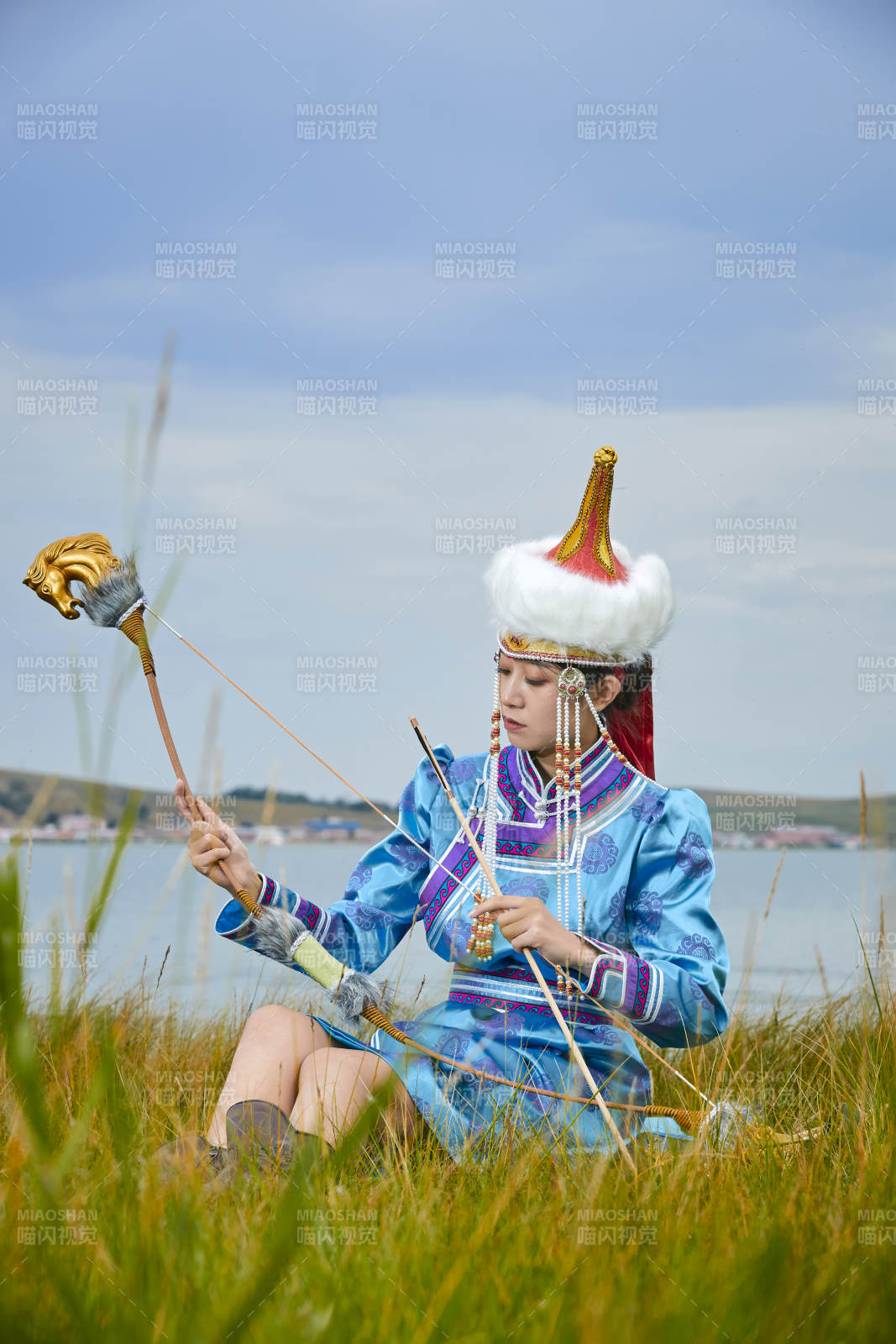 草原湖畔身穿蒙古族饰手持弓箭的蒙族少女图片