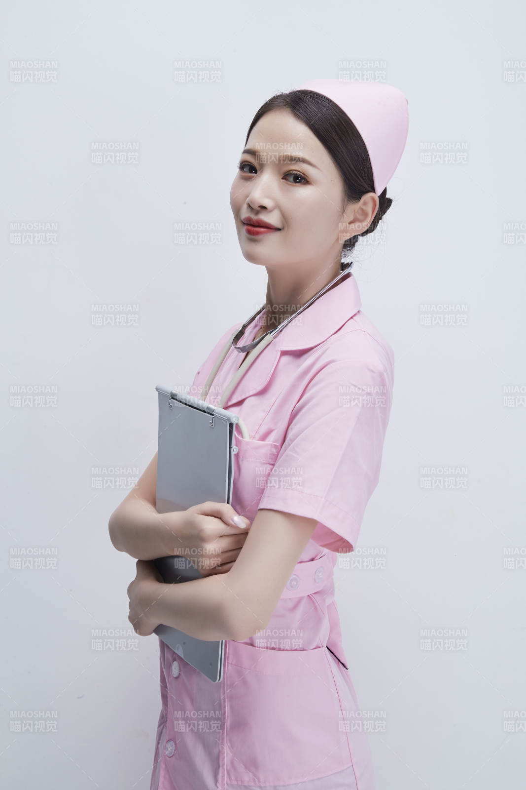 穿粉色护士服戴听诊器手持病历夹的医护人员图片