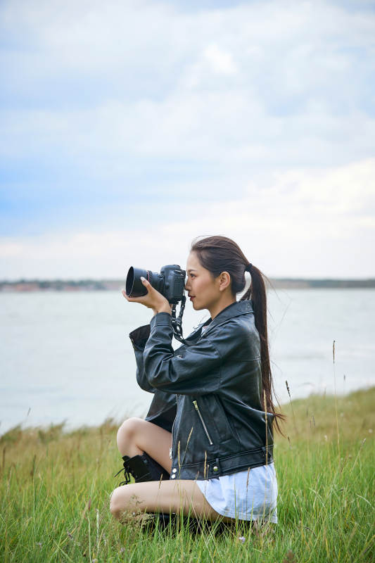 户外湖畔进行拍摄的亚洲青年女性摄影师图片