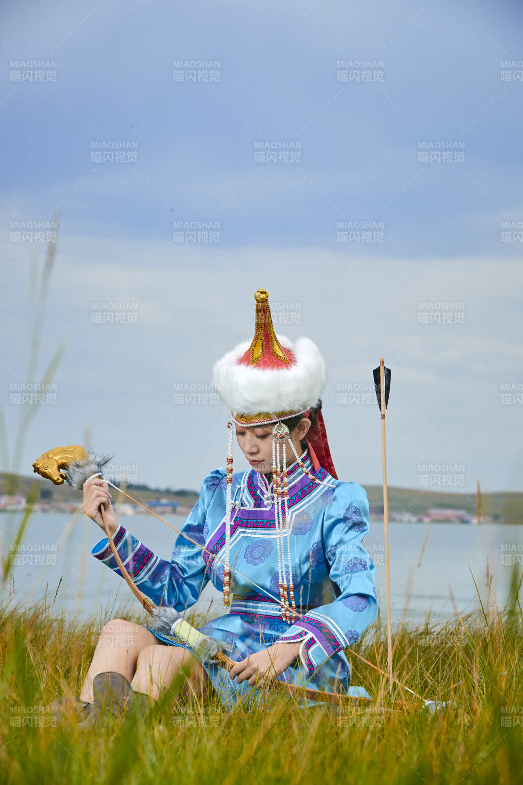 草原湖畔身穿蒙古族饰手持弓箭的蒙族少女图片