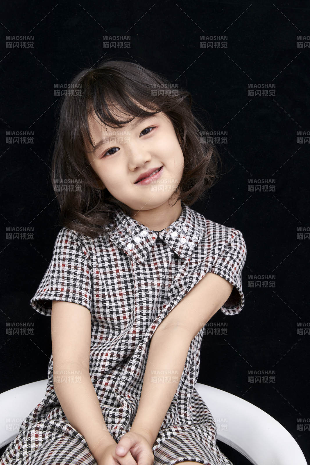 黑色背景里坐在凳子上的可爱的亚洲小女孩儿童图片