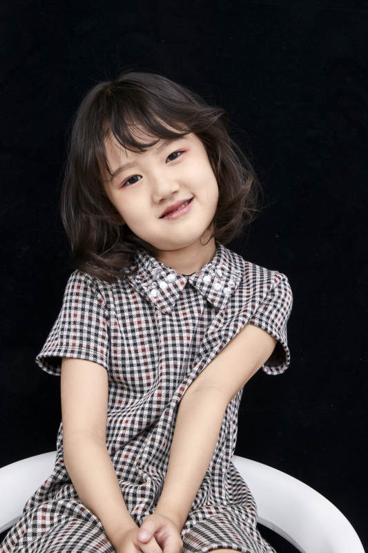 黑色背景里坐在凳子上的可爱的亚洲小女孩儿童图片