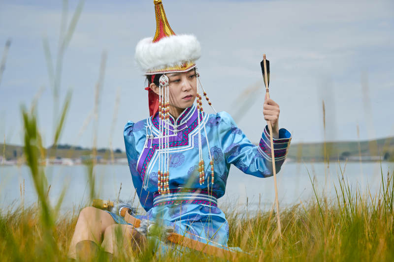草原湖畔身穿蒙古族饰手持弓箭的蒙族少女图片