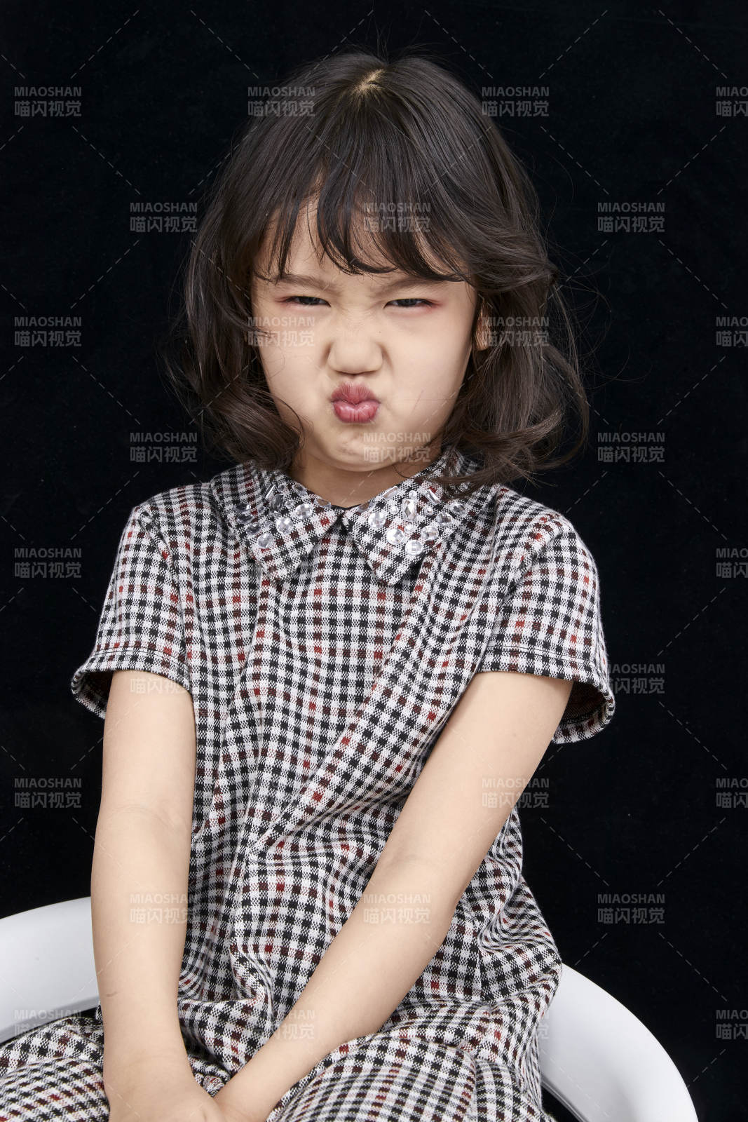 黑色背景里坐在凳子上的可爱的亚洲小女孩儿童图片