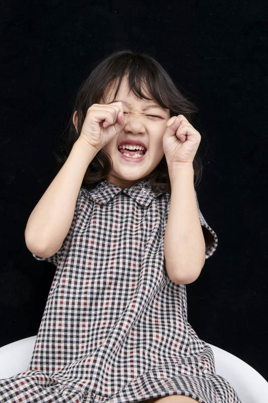 黑色背景里坐在凳子上的可爱的亚洲小女孩儿童图片