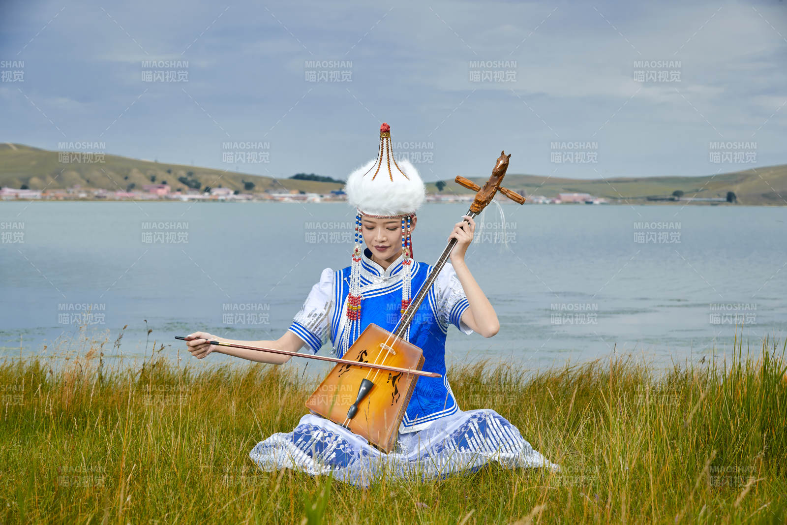 草原上穿蒙古族服饰拉马头琴的蒙族女乐手图片
