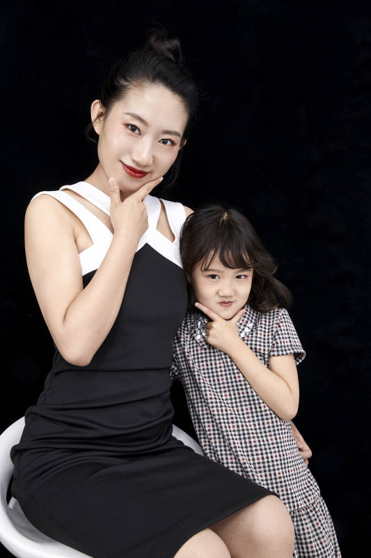 黑色背景的美丽妈妈与可爱女儿亲子人像图片