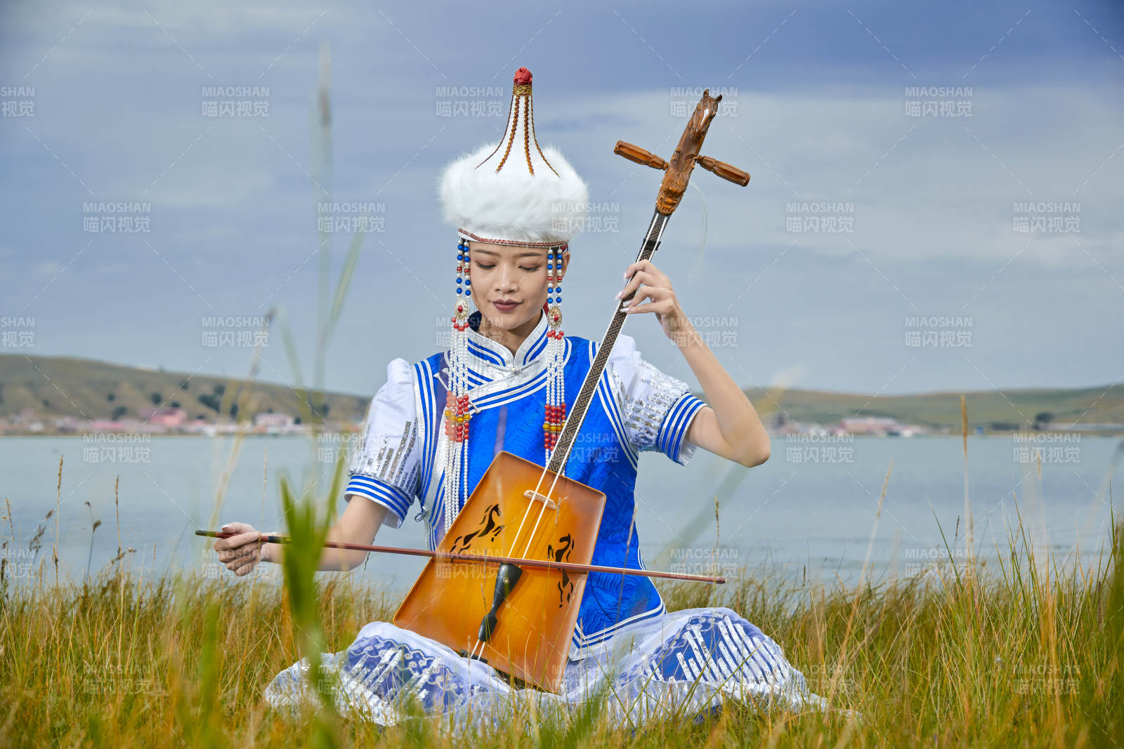 草原上穿蒙古族服饰拉马头琴的蒙族女乐手图片