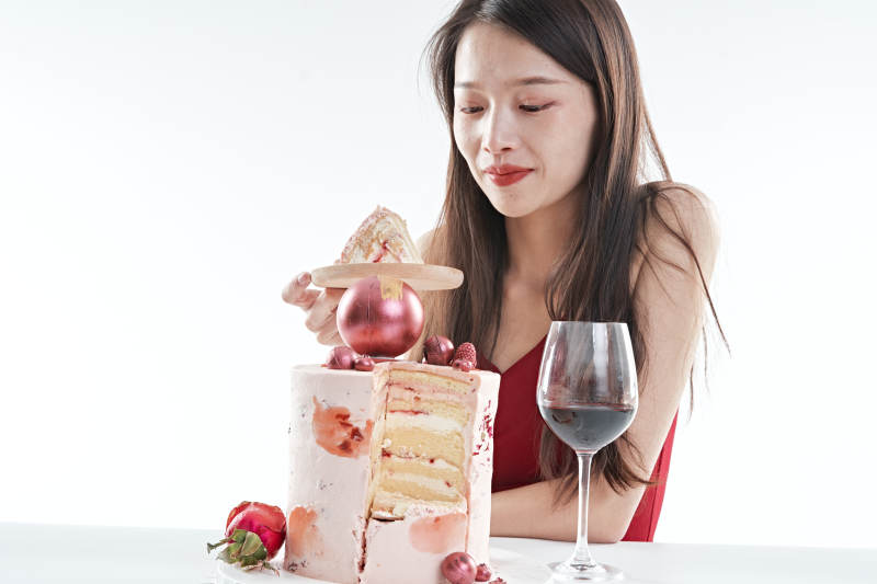 喝红酒品尝蛋糕的年轻女性图片