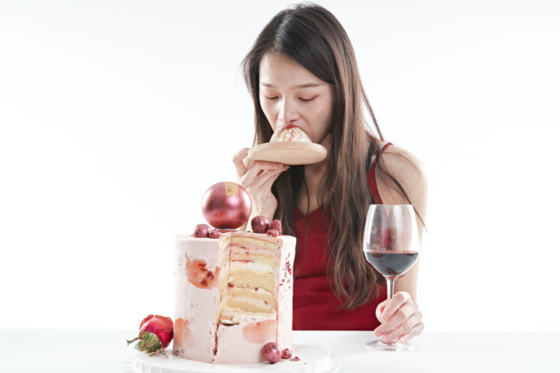 喝红酒品尝蛋糕的年轻女性图片
